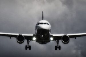 A dramatic view of an airplane landing with stormy clouds overhead, showcasing aviation in a monochrome scene.